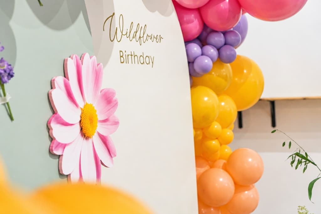 Decoración de cumpleaños infantil con arco de globos orgánicos y detalle de flor rosa